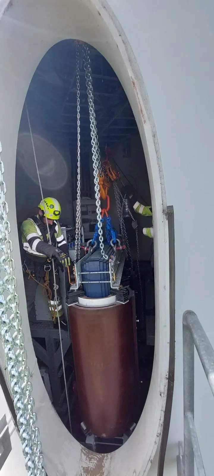 Technicians hoisting a heavy component inside a turbine tower