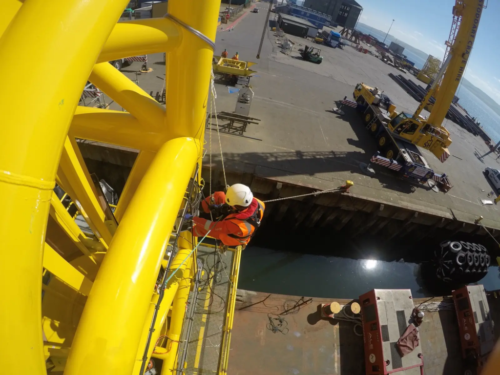 RAO Technician on a Yellow Offshore Structure in Port, Next to a Crane