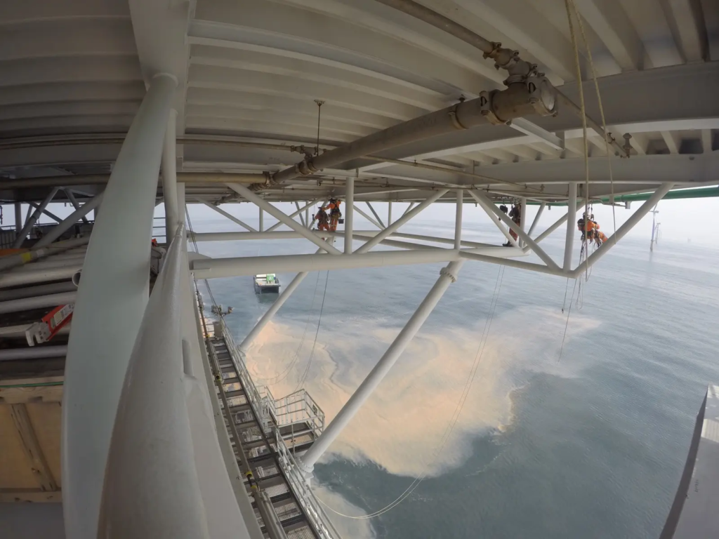 Techniciens sur cordes sous le pont d’une plateforme offshore
