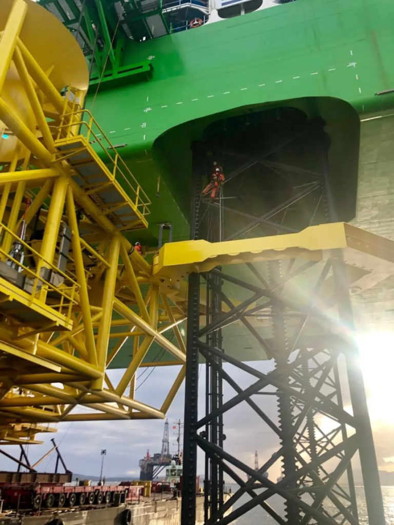 Technicien cordiste sur la structure d’une fondation offshore dans un port