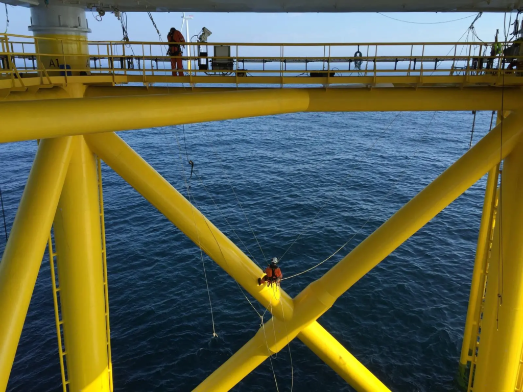 Technicien sur la structure en treillis jaune d’une fondation au-dessus de la mer