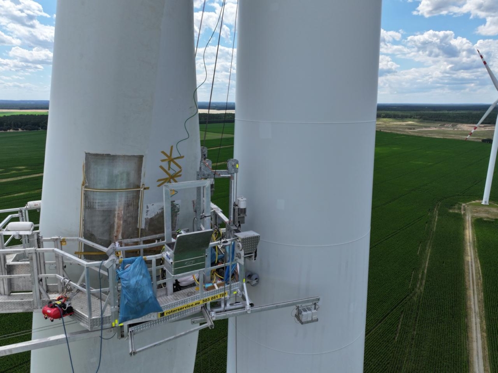 Service platform with a worker at a wind turbine blade, drone view